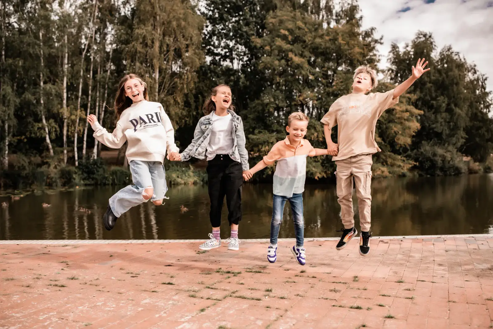 Vier Kinder springen am Seeufer in die Luft